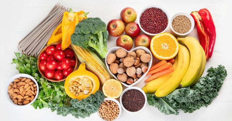 A white table topped with lots of fruits and vegetables.