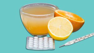 A bowl of broth, an orange and pills.