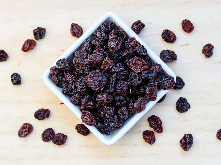 A white bowl of raisins on top of a table.
