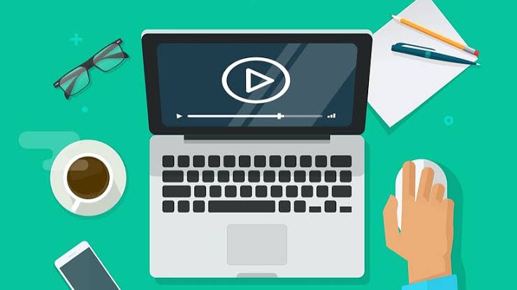 Laptop with play icon surrounded by office items on a teal background